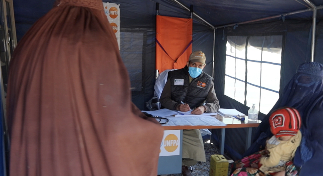 The head doctor at the Torkham reception centre clinic prescribes reproductive health medicines to a mother.