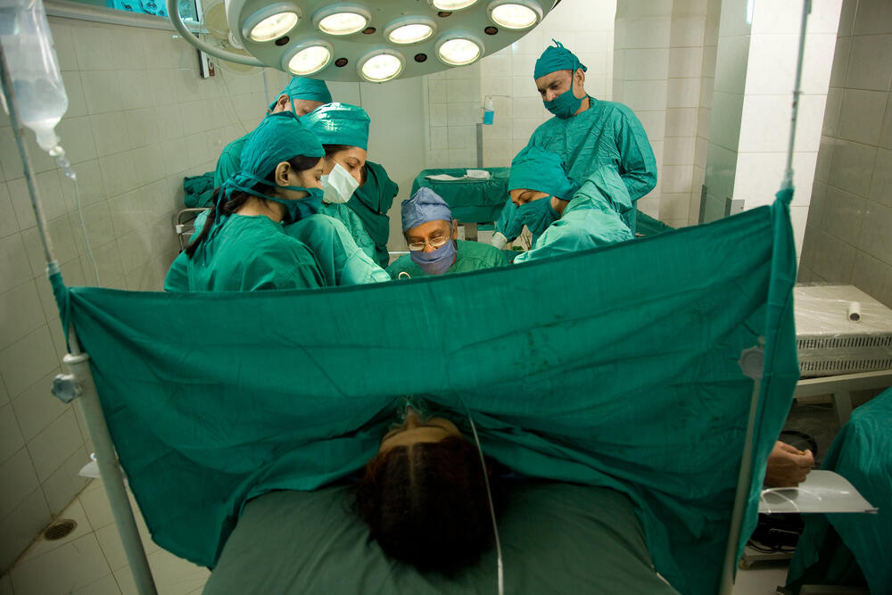 Hospital delivery room with a woman giving birth, with several health professionals working