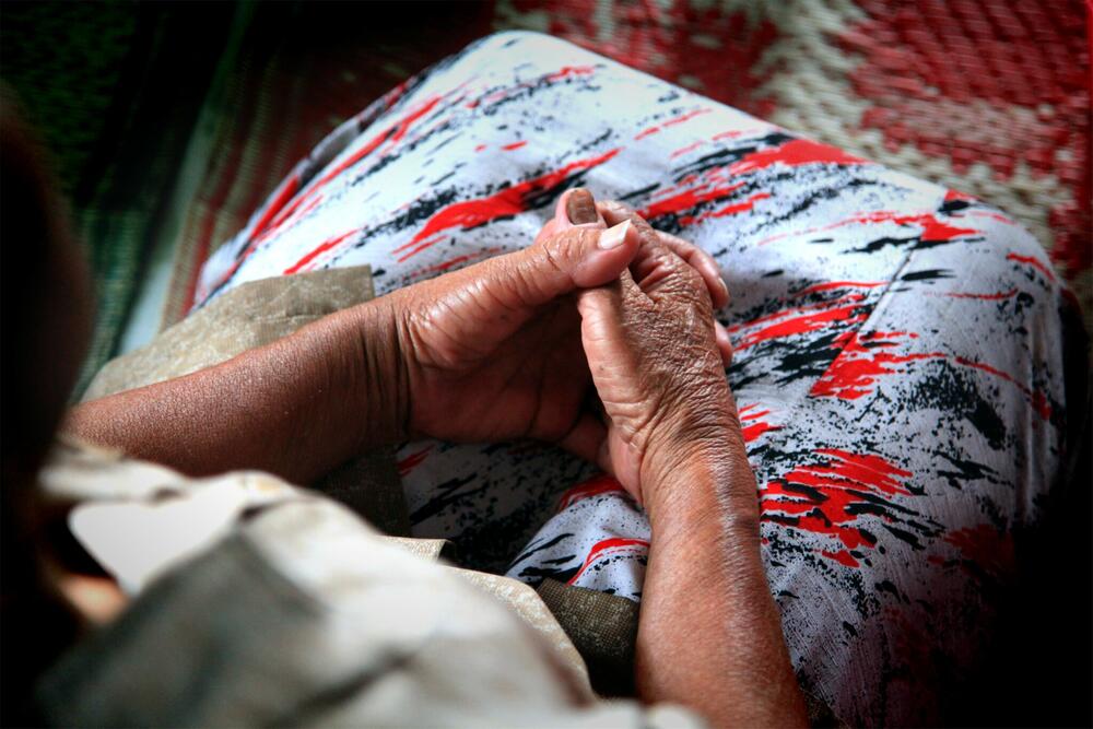 Close up of an old woman's hands, she is wearing a colorful skirt