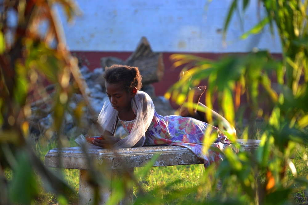 Girl lying on a bench outdoors using her phone