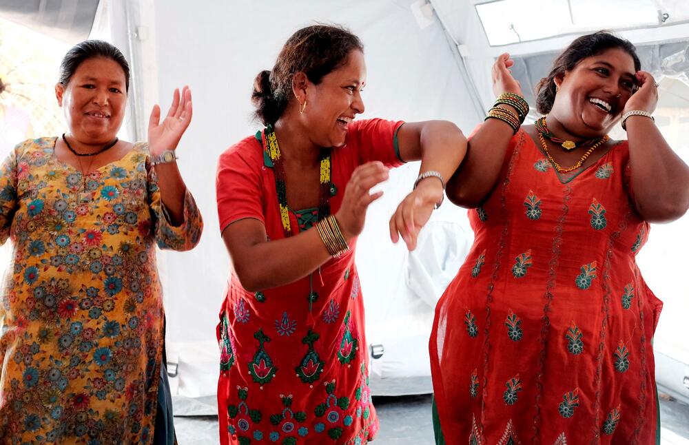 Three women wearing vibrant color clothes and smiling