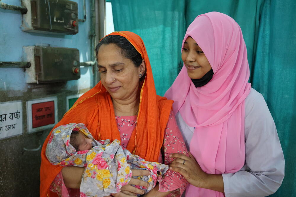 Two women wearing head scarf and one is holding a baby