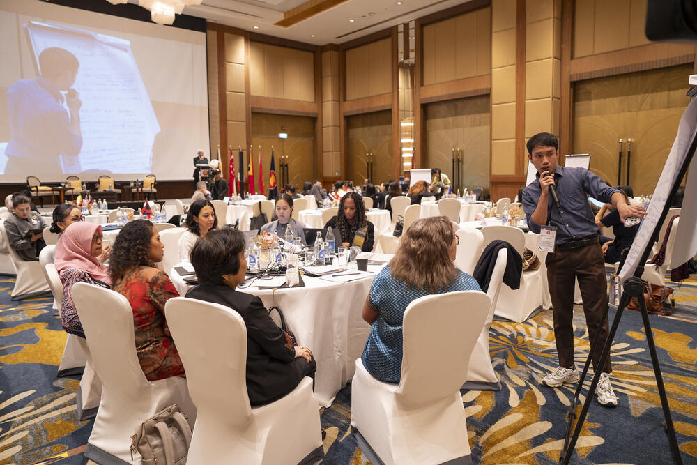People in a meeting room, sitting at a round table and discussing