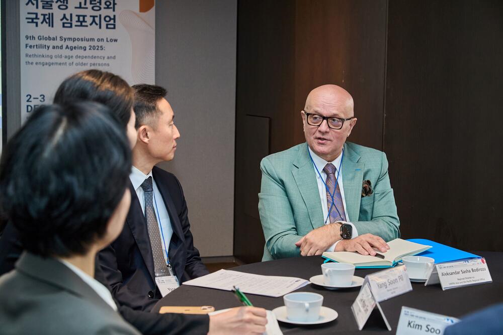 People in a meeting room, sitting at a table and discussing