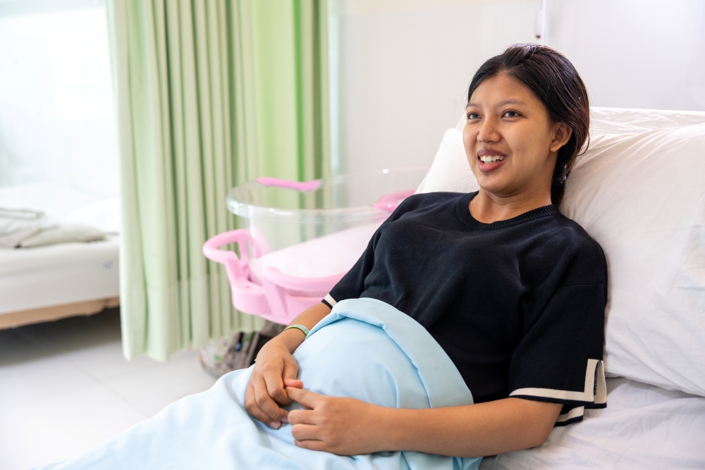 Mother who just gave birth at the hospital in bed and smiling
