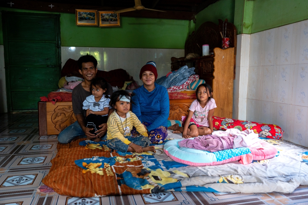 Family in a very simple house with father, mother, three girls and one baby