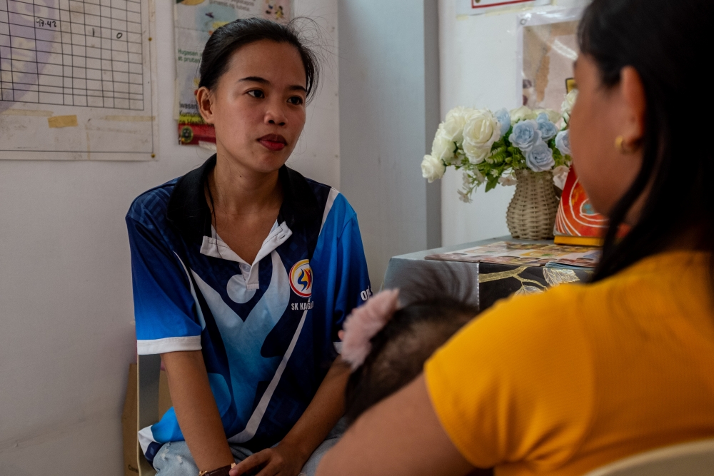 Young woman speaking to a mother holding her baby