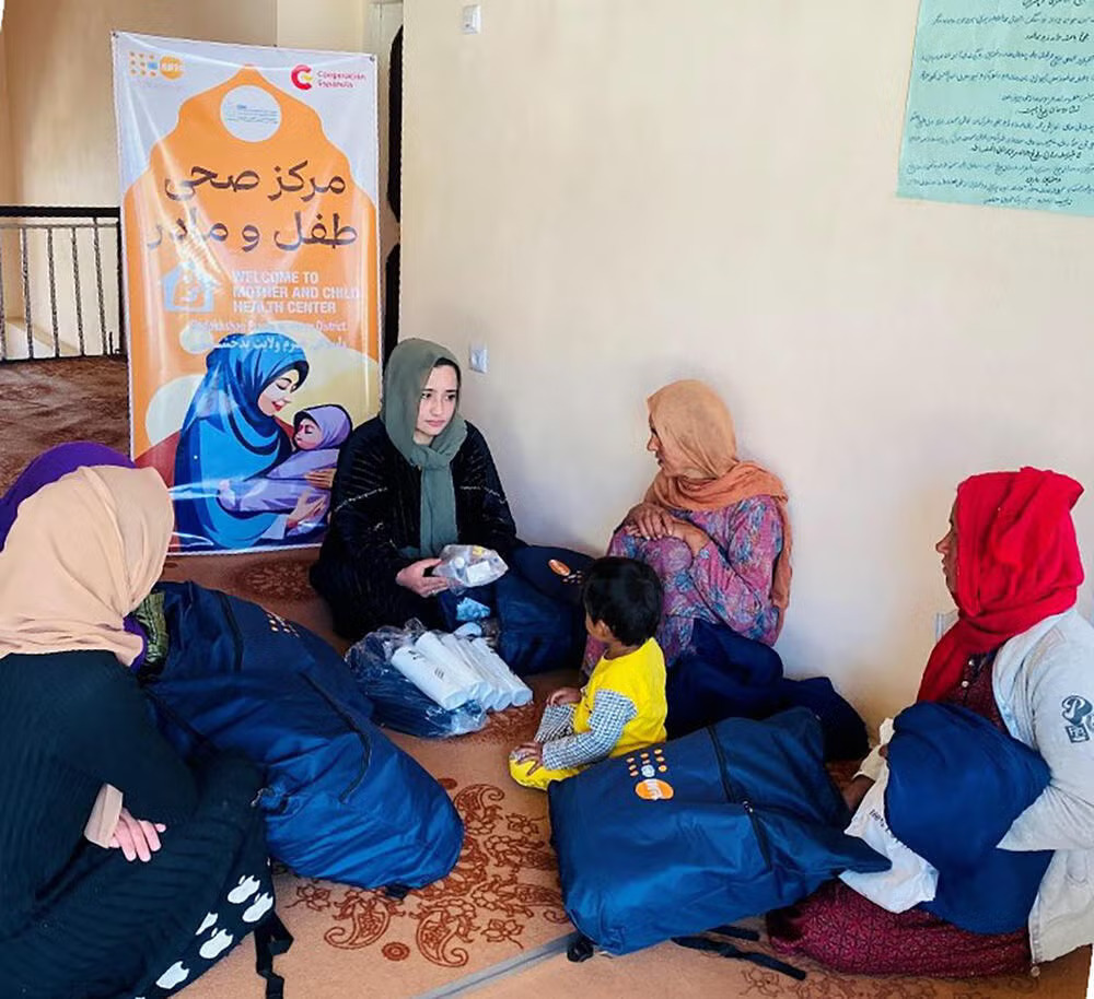 A health worker shows the contents of a Dignity Kit to women.