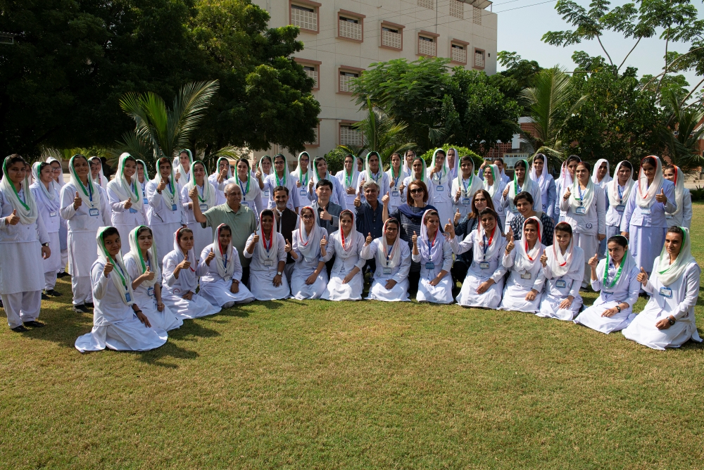 A group of health professionals in a semi-circle outside a health facility