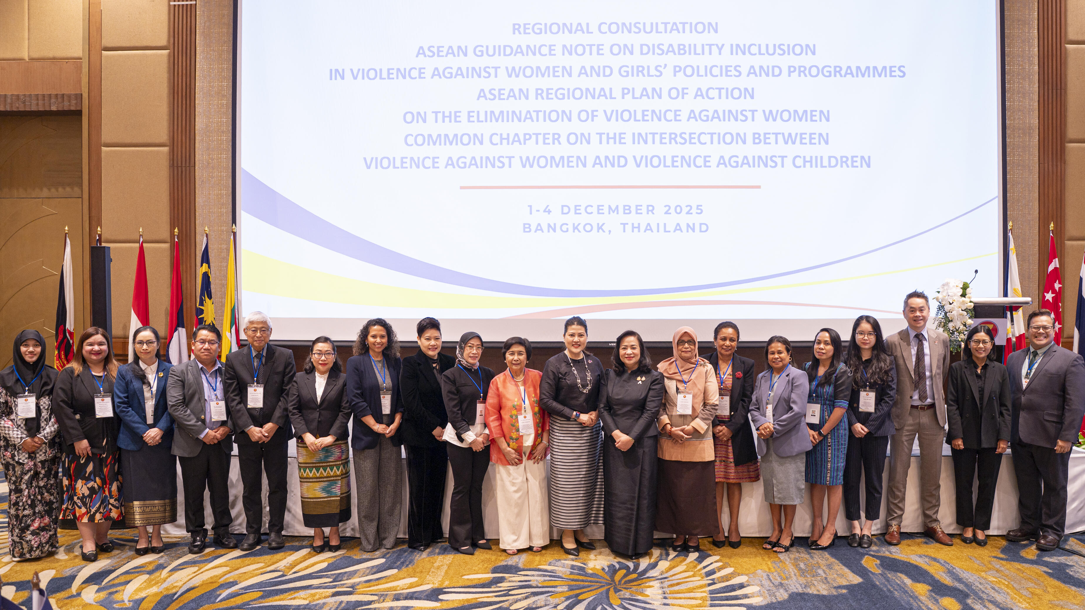 Group photo in front of a big projector screen and countries flags on the sides
