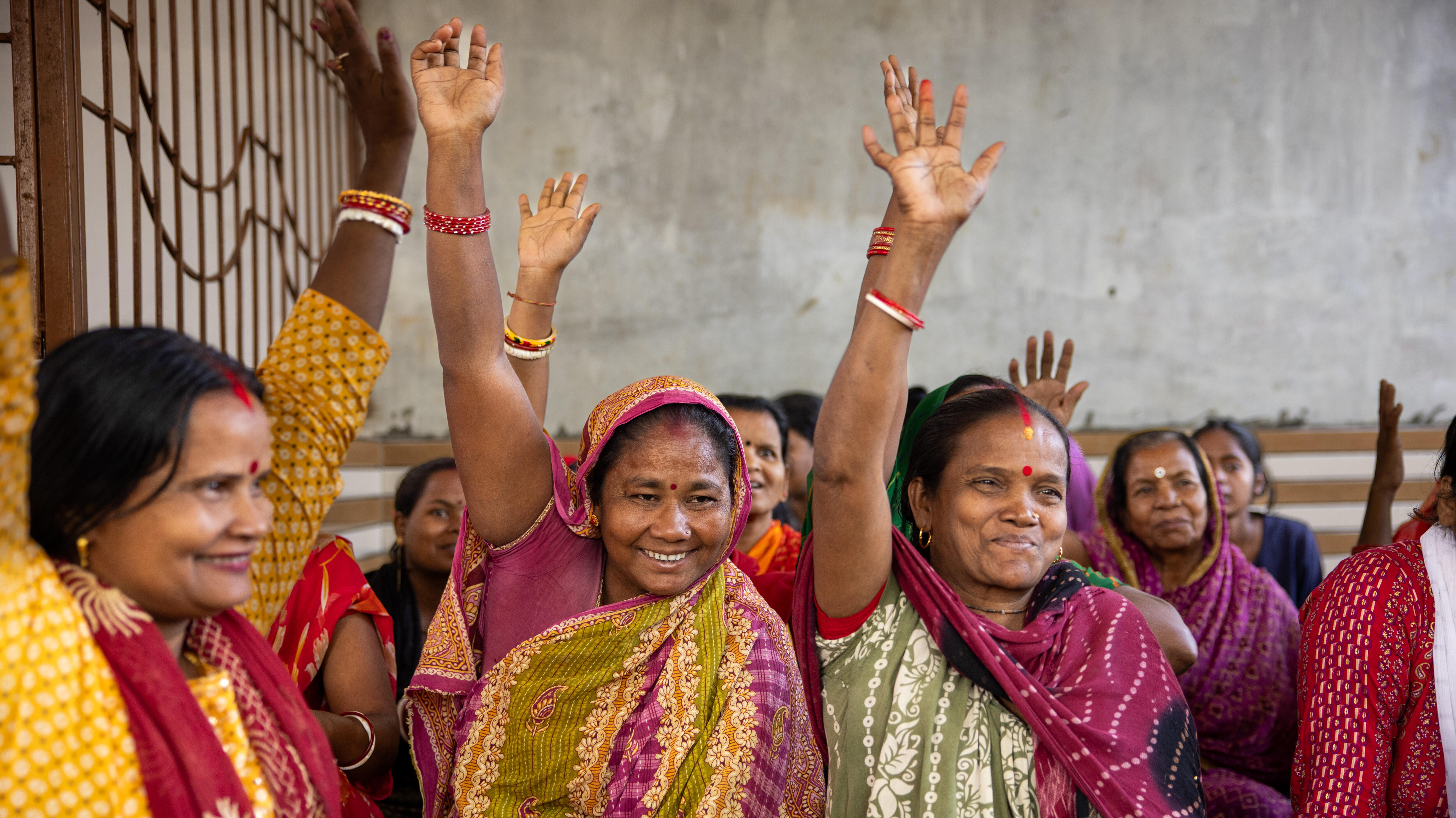 A group of Nepalese women smiling and waving their hands