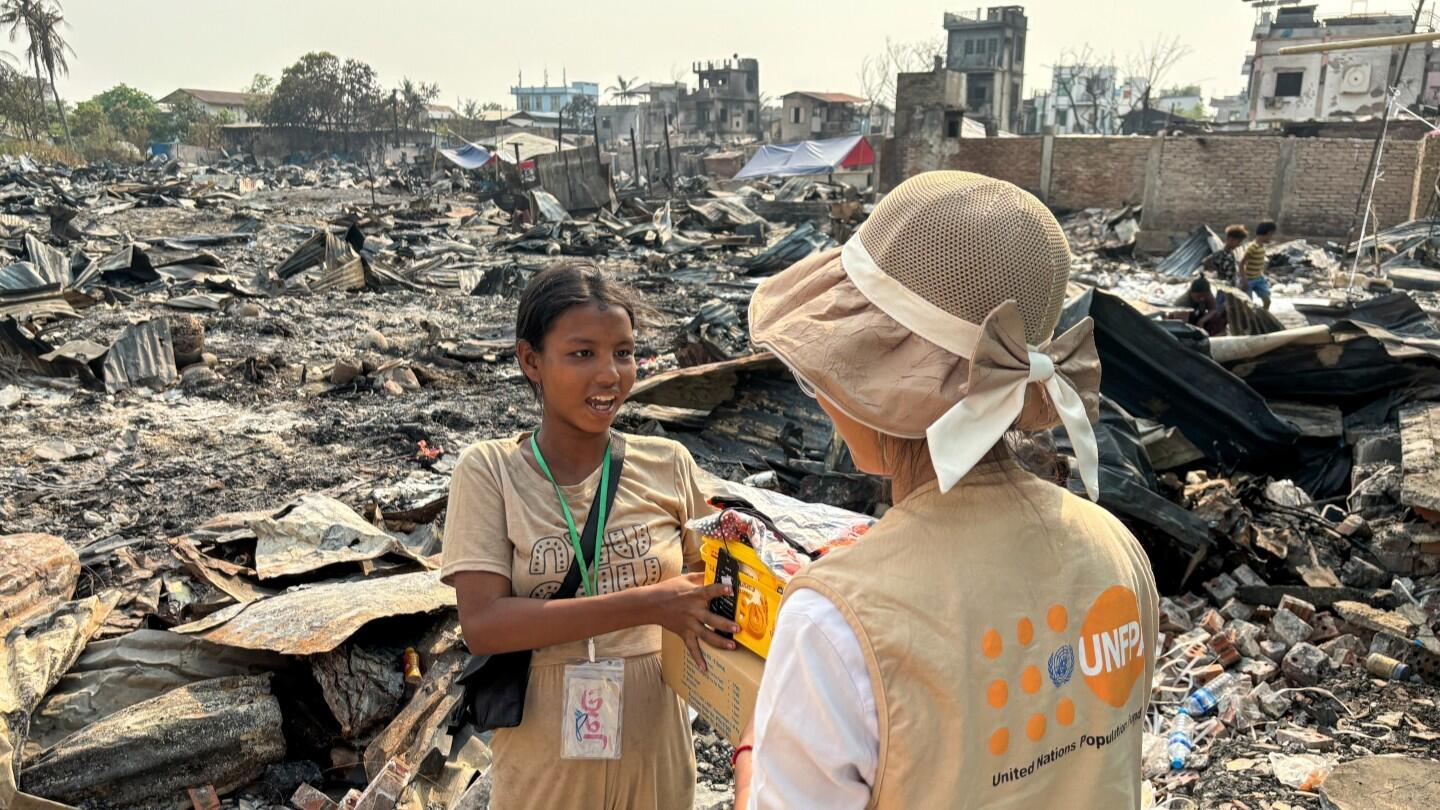A UNFPA frontline responder provides support and supplies to a young girl amidst debris, after the earthquake that struck Myanmar earlier this year (Photo: UNFPA Myanmar)