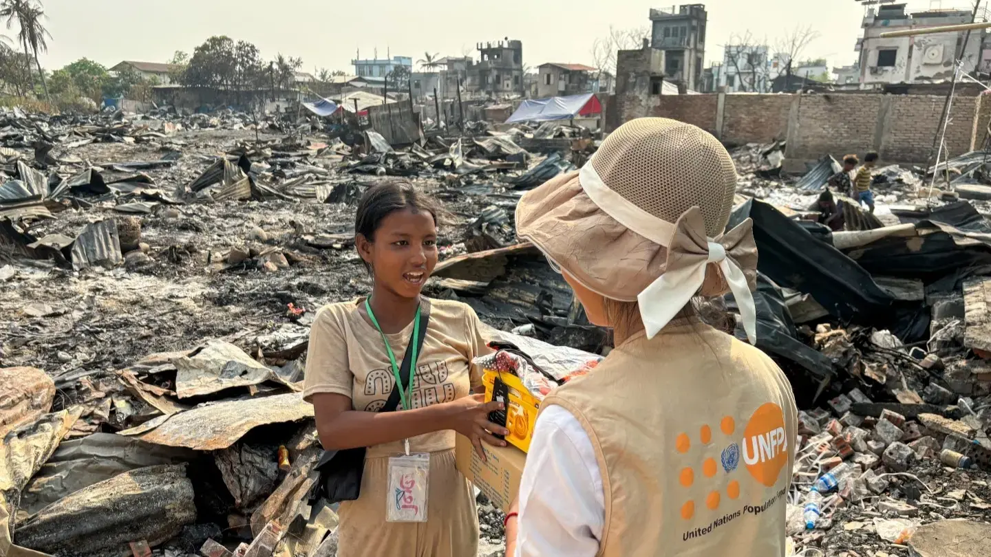 A UNFPA frontline responder provides support and supplies to a young girl amidst debris, after the earthquake that struck Myanmar earlier this year (Photo: UNFPA Myanmar)